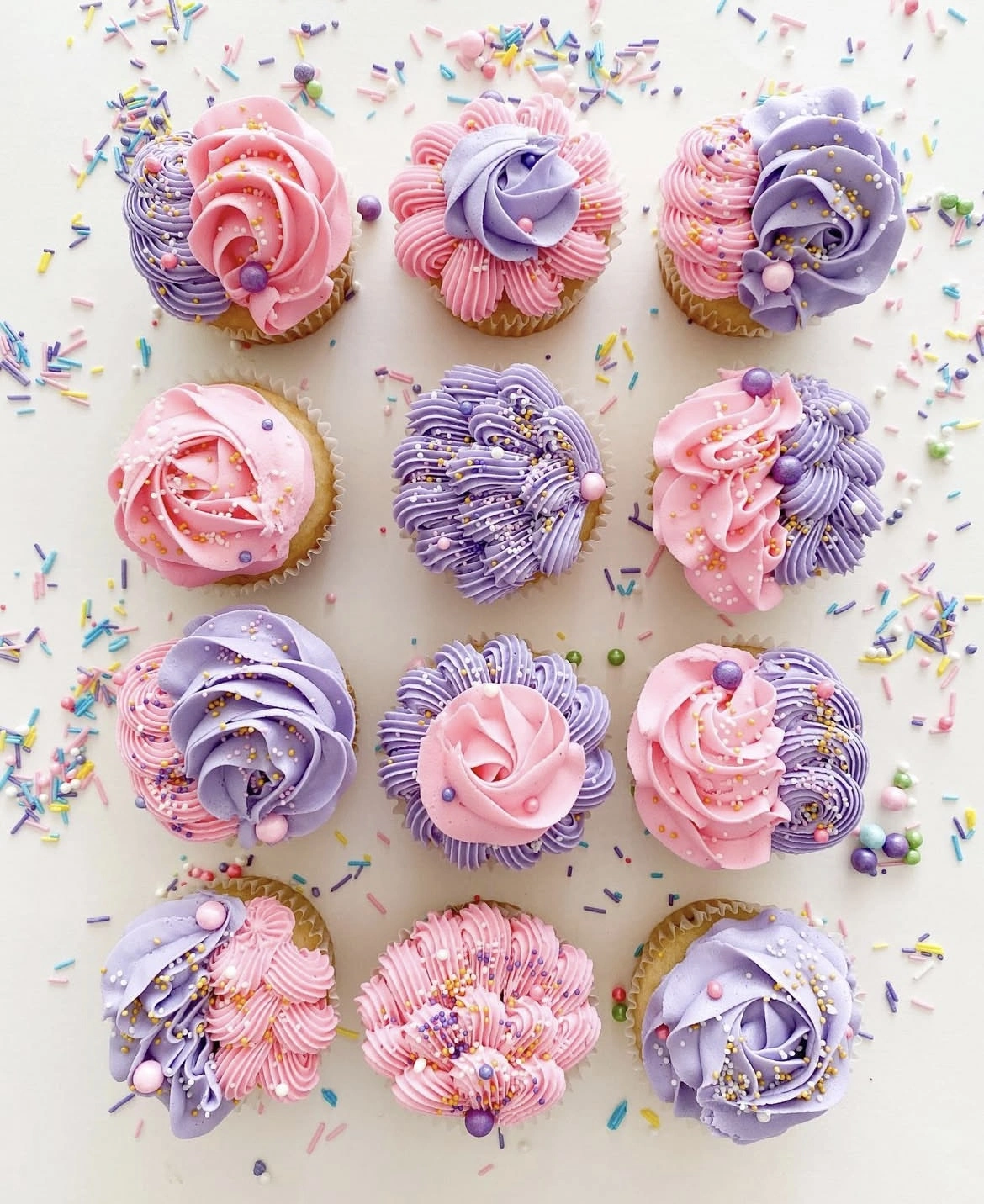 Assorted cupcakes decorated with pink and purple frosting and sprinkles