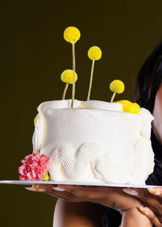 Minimalist white buttercream celebration cake with floral decorations and modern cake styling
