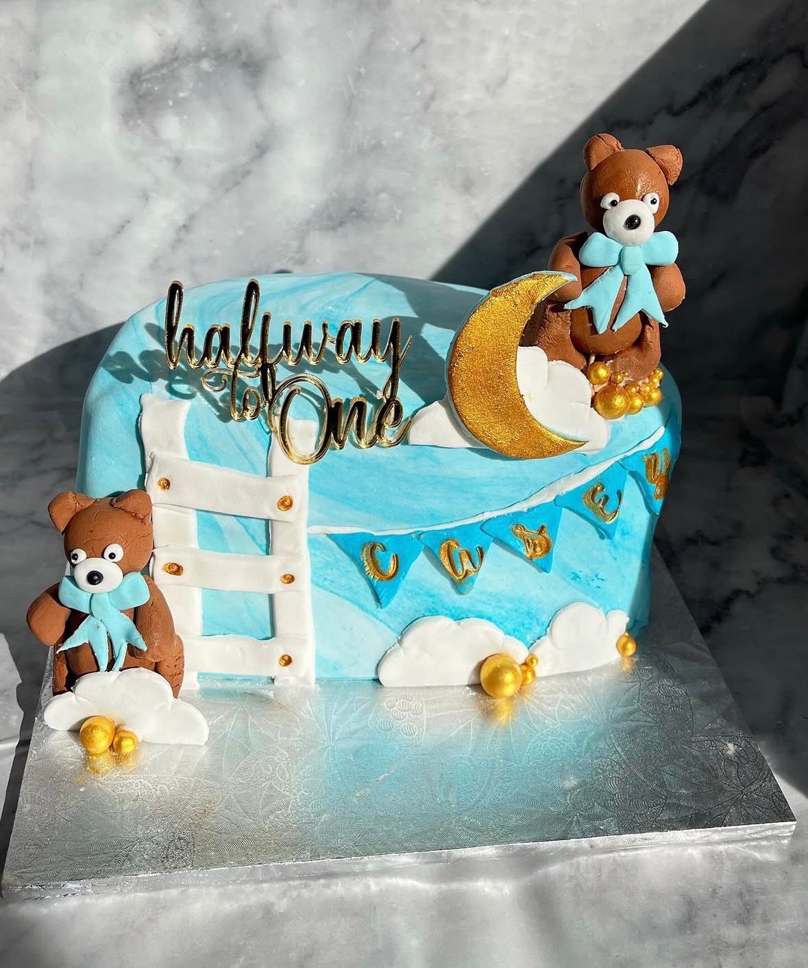 Blue half birthday cake with teddy bears, clouds and moon decorations